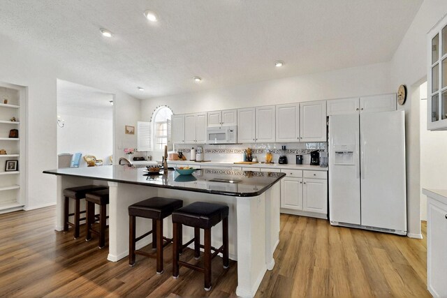 10320 Durham St NW, Albuquerque, NM 87114 - kitchen featuring white appliances, a kitchen bar, light wood-style flooring, white cabinetry, and an island with sink