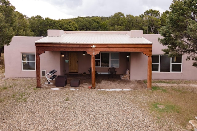 13 Asher Ln, Tijeras, NM 87059 - rear view of house featuring stucco siding, a wooded view, and metal roof