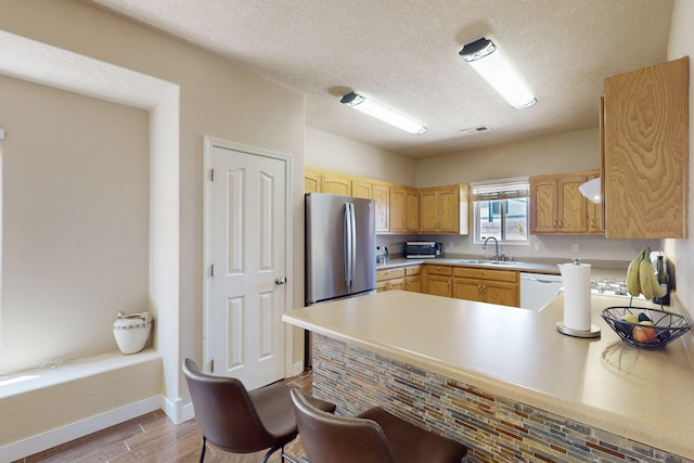 1723 Avenida Real, Albuquerque, NM 87105 - kitchen with freestanding refrigerator, a sink, a peninsula, wood finished floors, and a textured ceiling