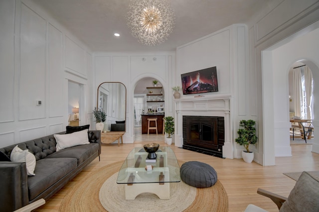 223 14th St NW, Albuquerque, NM 87104 - living room featuring a decorative wall, arched walkways, a chandelier, a fireplace with flush hearth, and light wood finished floors
