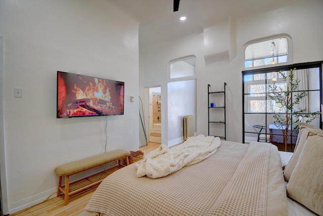 223 14th St NW, Albuquerque, NM 87104 - bedroom with radiator, light wood-style floors, a high ceiling, baseboards, and ensuite bathroom