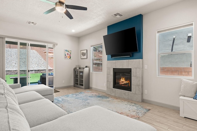 1661 Camino Culiacan, Los Lunas, NM 87031 - living room featuring a ceiling fan, a textured ceiling, healthy amount of natural light, wood finished floors, and a tile fireplace