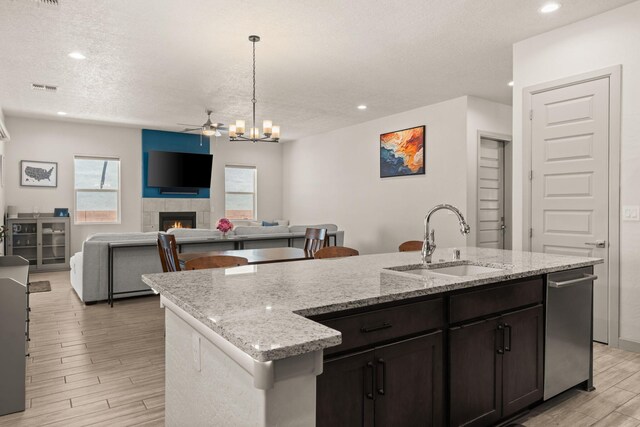 1661 Camino Culiacan, Los Lunas, NM 87031 - kitchen with a sink, a fireplace, light wood finished floors, a kitchen island with sink, and a textured ceiling