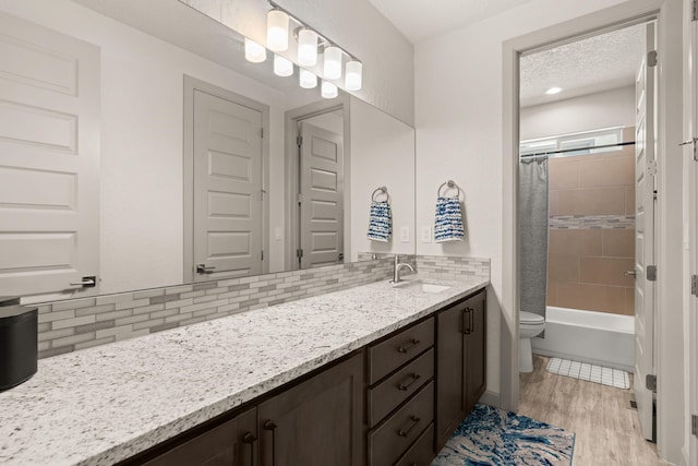 1661 Camino Culiacan, Los Lunas, NM 87031 - bathroom featuring backsplash, wood finished floors, vanity, toilet, and shower / bath combo with shower curtain