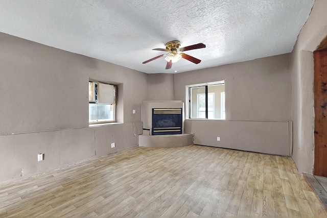 1237 Gabaldon Rd, Belen, NM 87002 - unfurnished living room featuring wood finished floors, plenty of natural light, a glass covered fireplace, and a textured ceiling