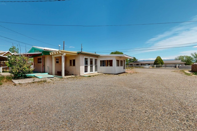 1237 Gabaldon Rd, Belen, NM 87002 - rear view of house with stucco siding, driveway, and a patio area