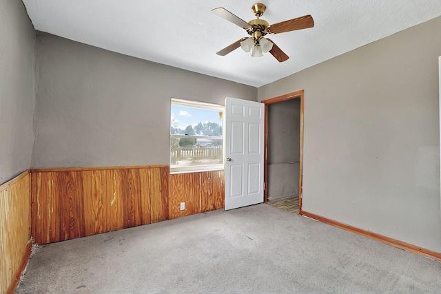 1237 Gabaldon Rd, Belen, NM 87002 - carpeted spare room featuring wood walls, a ceiling fan, and a wainscoted wall