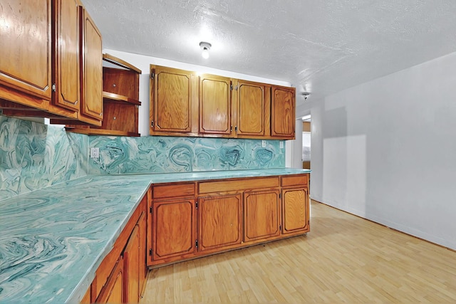 1237 Gabaldon Rd, Belen, NM 87002 - kitchen with brown cabinets, light wood finished floors, open shelves, light countertops, and a textured ceiling