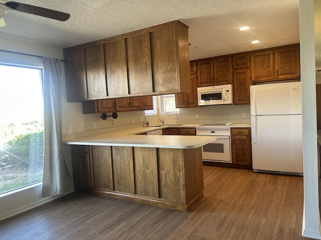 2833 Tiffany Rd, Tucumcari, NM 88401 - kitchen with white appliances, dark wood-type flooring, a peninsula, a textured ceiling, and light countertops