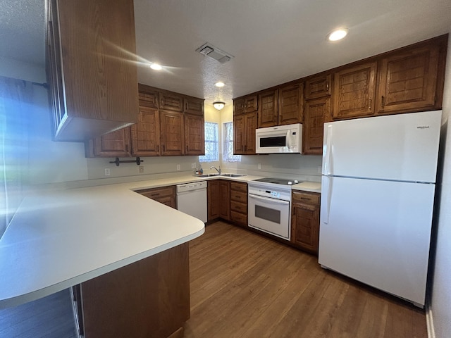 2833 Tiffany Rd, Tucumcari, NM 88401 - kitchen with white appliances, a sink, wood finished floors, a peninsula, and light countertops