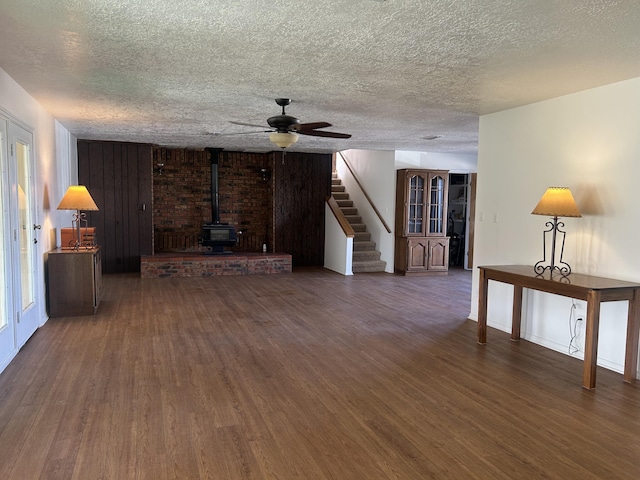 2833 Tiffany Rd, Tucumcari, NM 88401 - unfurnished living room with a wood stove, wood finished floors, stairs, a ceiling fan, and a textured ceiling