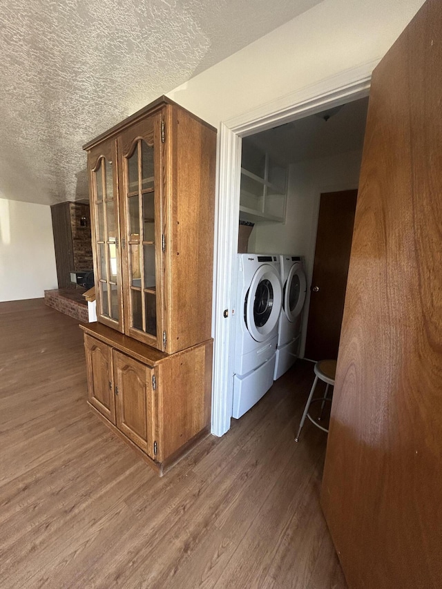 2833 Tiffany Rd, Tucumcari, NM 88401 - washroom featuring separate washer and dryer, wood finished floors, a textured ceiling, and a fireplace