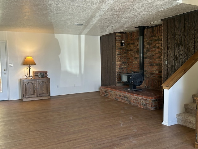 2833 Tiffany Rd, Tucumcari, NM 88401 - unfurnished living room featuring wood finished floors, a wood stove, a textured ceiling, stairs, and baseboards