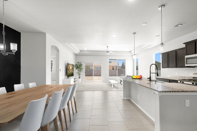 6 Margarita Cir, Los Lunas, NM 87031 - kitchen with appliances with stainless steel finishes, a tray ceiling, arched walkways, ceiling fan, and light stone countertops