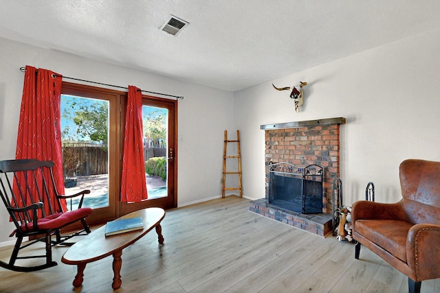 8224 Bret Pl NE, Albuquerque, NM 87109 - living area with wood finished floors, a brick fireplace, baseboards, and a textured ceiling