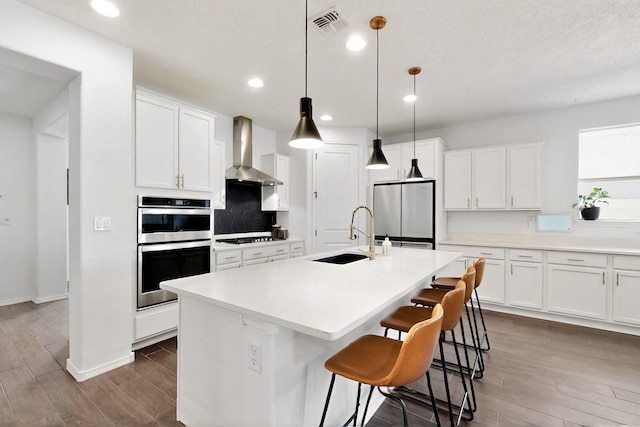 1605 Copper Mountain Trl NW, Albuquerque, NM 87120 - kitchen with a sink, wall chimney exhaust hood, appliances with stainless steel finishes, dark wood-style flooring, and white cabinetry