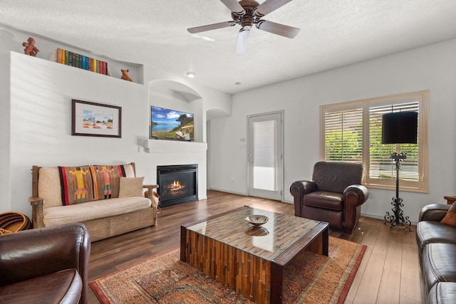 3827 Fox Sparrow Trl NW, Albuquerque, NM 87120 - living area featuring wood finished floors, a glass covered fireplace, a textured ceiling, and a ceiling fan