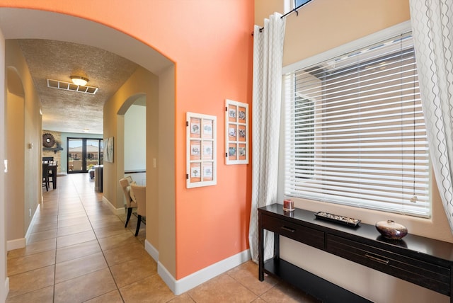 2659 Vista Manzano Loop NE, Rio Rancho, NM 87144 - hall with arched walkways, light tile patterned floors, baseboards, and a textured ceiling