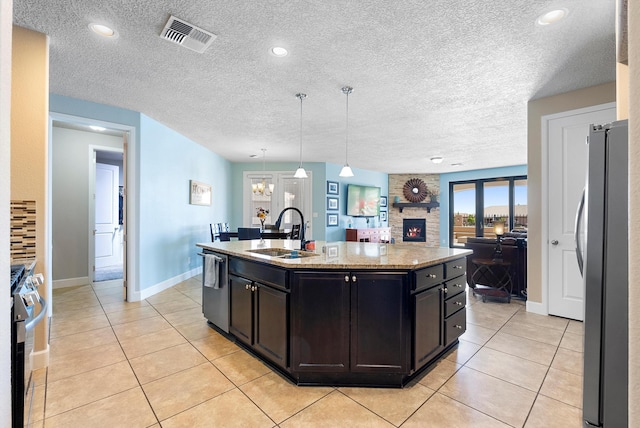 2659 Vista Manzano Loop NE, Rio Rancho, NM 87144 - kitchen featuring a sink, appliances with stainless steel finishes, light tile patterned floors, an island with sink, and light stone counters