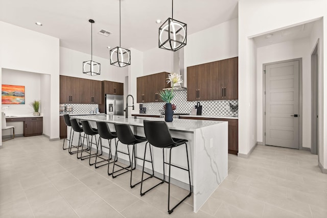 1413 6th St SE, Rio Rancho, NM 87124 - kitchen with stainless steel fridge with ice dispenser, wall chimney range hood, light countertops, decorative backsplash, and a breakfast bar area