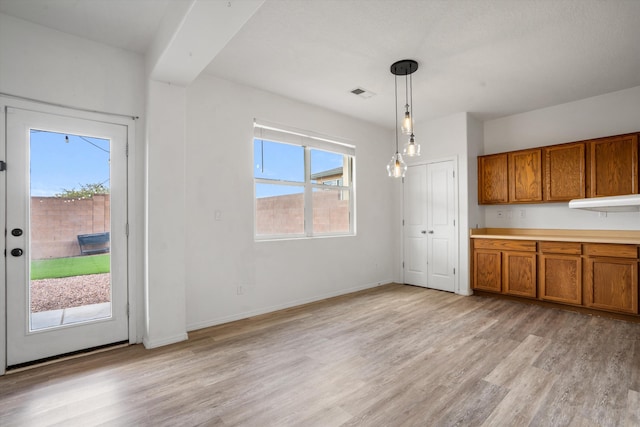 3702 Buckskin Loop NE, Rio Rancho, NM 87144 - kitchen featuring brown cabinets, light wood-type flooring, pendant lighting, baseboards, and light countertops