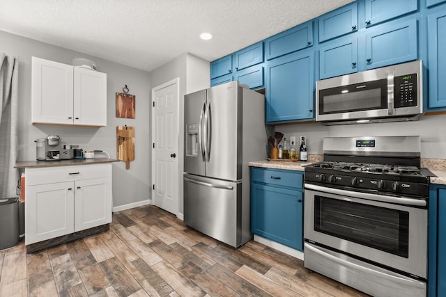 1227 Desert Paintbrush Loop, Rio Rancho, NM 87144 - kitchen featuring appliances with stainless steel finishes, blue cabinets, dark wood-style floors, light countertops, and a textured ceiling