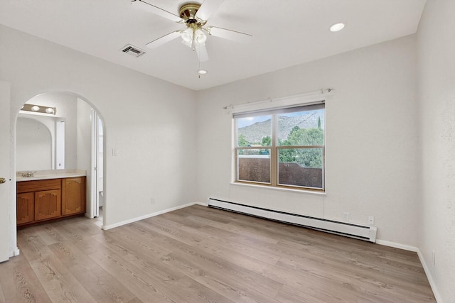 2517 Georgene Dr NE, Albuquerque, NM 87112 - unfurnished bedroom with baseboard heating, arched walkways, light wood finished floors, connected bathroom, and a ceiling fan