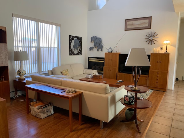 2517 Georgene Dr NE, Albuquerque, NM 87112 - living room featuring a glass covered fireplace, a baseboard radiator, and light tile patterned floors