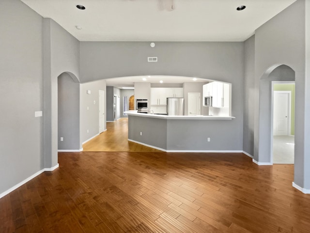 1713 Caramesa Dr SE, Rio Rancho, NM 87124 - unfurnished living room featuring arched walkways, wood finished floors, baseboards, a high ceiling, and recessed lighting