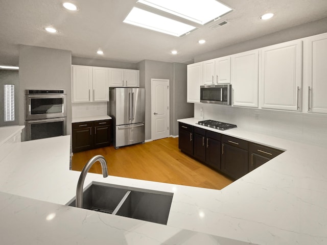 1713 Caramesa Dr SE, Rio Rancho, NM 87124 - kitchen with stainless steel appliances, a sink, white cabinets, light wood-style floors, and recessed lighting