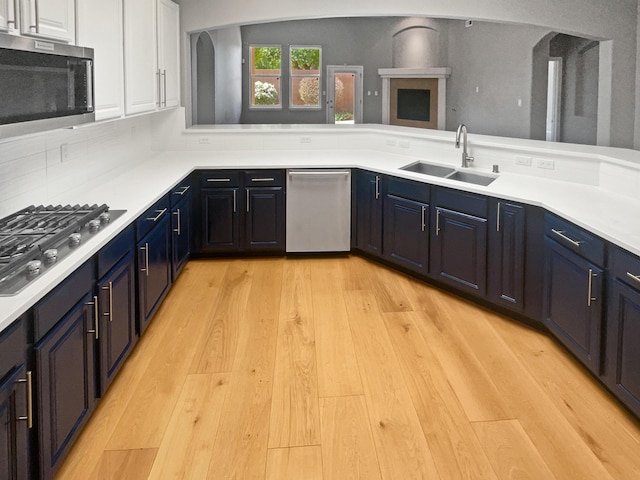 1713 Caramesa Dr SE, Rio Rancho, NM 87124 - kitchen with stainless steel appliances, a sink, white cabinets, light countertops, and light wood-type flooring