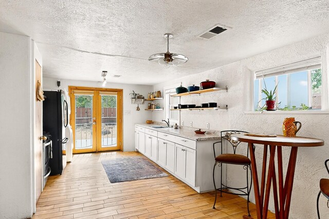 1508 Barelas Rd SW, Albuquerque, NM 87102 - kitchen featuring a sink, plenty of natural light, a textured wall, light wood-style floors, and a textured ceiling