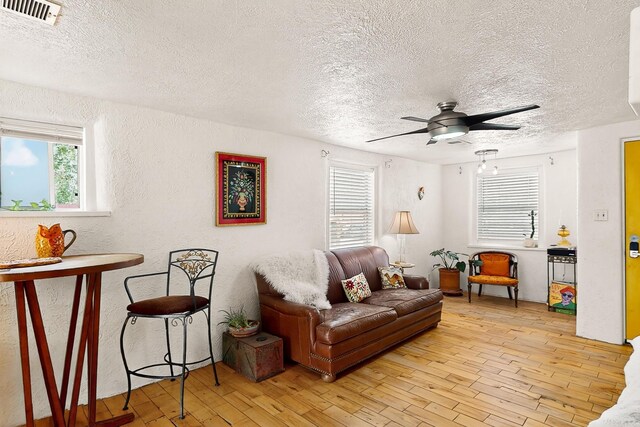 1508 Barelas Rd SW, Albuquerque, NM 87102 - living area with a textured ceiling, plenty of natural light, a ceiling fan, light wood finished floors, and a textured wall
