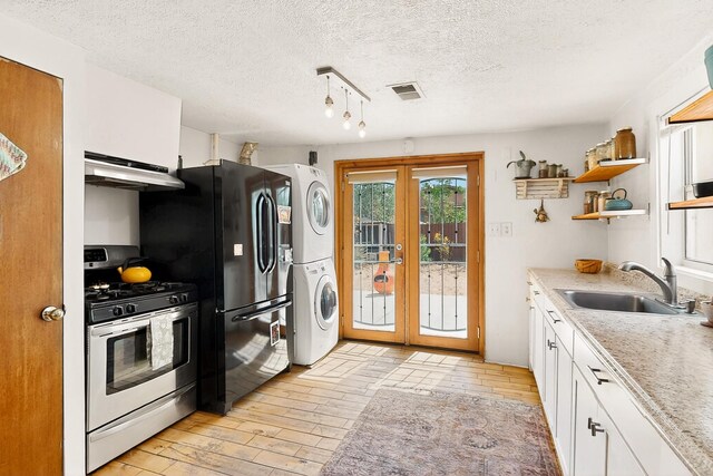 1508 Barelas Rd SW, Albuquerque, NM 87102 - kitchen featuring gas stove, a sink, under cabinet range hood, stacked washing machine and dryer, and french doors