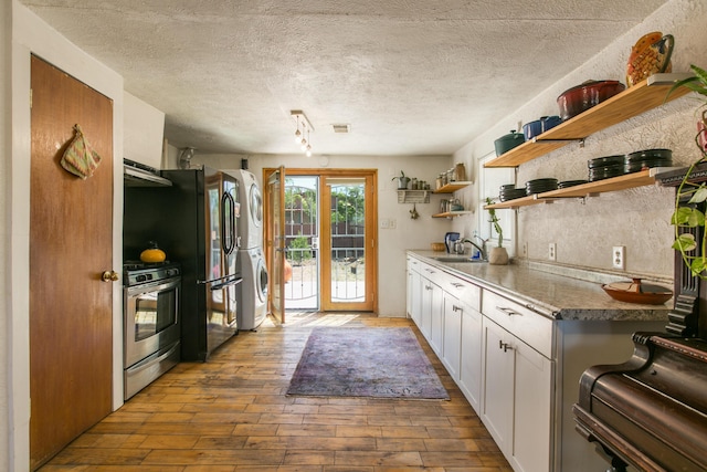 1508 Barelas Rd SW, Albuquerque, NM 87102 - kitchen featuring gas range, stacked washing machine and dryer, open shelves, hardwood / wood-style floors, and a sink