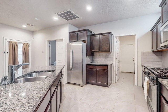 1472 Tierra Verde Loop, Los Lunas, NM 87031 - kitchen with freestanding refrigerator, range with gas stovetop, a sink, decorative backsplash, and dark brown cabinets