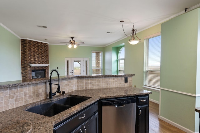9200 Saguaro St NW, Albuquerque, NM 87114 - kitchen with stainless steel dishwasher, a sink, tasteful backsplash, wood finished floors, and a brick fireplace