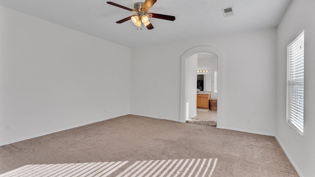 1023 Marapi St NW, Albuquerque, NM 87120 - unfurnished room featuring arched walkways, a ceiling fan, light colored carpet, and healthy amount of natural light
