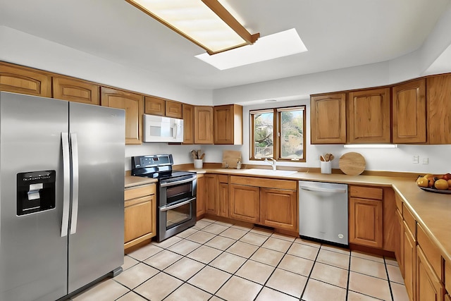 1704 Quail Run Ct NE, Albuquerque, NM 87122 - kitchen with stainless steel appliances, a sink, a skylight, light countertops, and brown cabinets