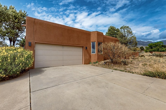 1704 Quail Run Ct NE, Albuquerque, NM 87122 - adobe home featuring stucco siding, an attached garage, concrete driveway, and a mountain view