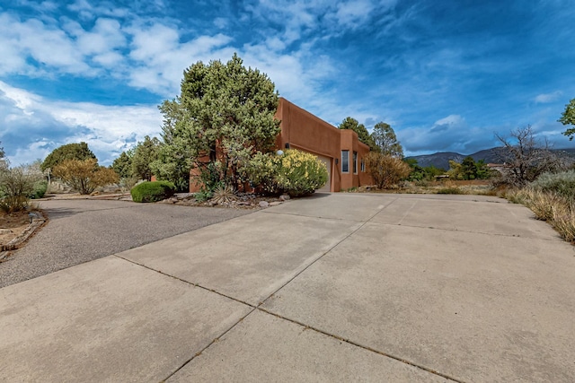 1704 Quail Run Ct NE, Albuquerque, NM 87122 - view of home's exterior featuring driveway, an attached garage, a mountain view, and stucco siding
