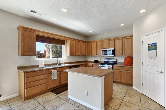 1412 Wind Ridge Dr NW, Albuquerque, NM 87120 - kitchen with stainless steel appliances, recessed lighting, a center island, a textured ceiling, and brown cabinets
