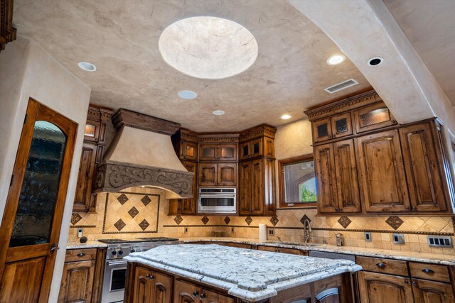 9301 Black Farm Ln NW, Albuquerque, NM 87114 - kitchen with high end stove, custom exhaust hood, backsplash, a kitchen island, and recessed lighting