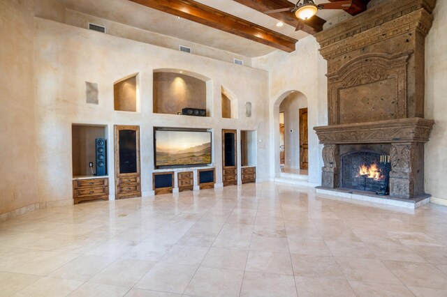 9301 Black Farm Ln NW, Albuquerque, NM 87114 - unfurnished living room with beamed ceiling, a high ceiling, ceiling fan, arched walkways, and a fireplace
