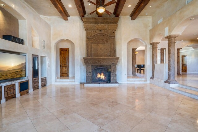 9301 Black Farm Ln NW, Albuquerque, NM 87114 - unfurnished living room featuring a towering ceiling, ceiling fan, beam ceiling, arched walkways, and a large fireplace