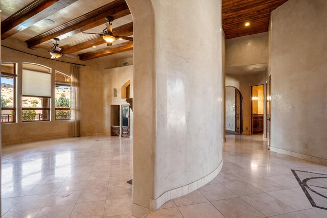 9301 Black Farm Ln NW, Albuquerque, NM 87114 - unfurnished room featuring arched walkways, a ceiling fan, a towering ceiling, tile patterned flooring, and a wood ceiling with exposed beams