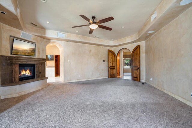 9301 Black Farm Ln NW, Albuquerque, NM 87114 - unfurnished living room with arched walkways, a glass covered fireplace, a ceiling fan, recessed lighting, and carpet flooring