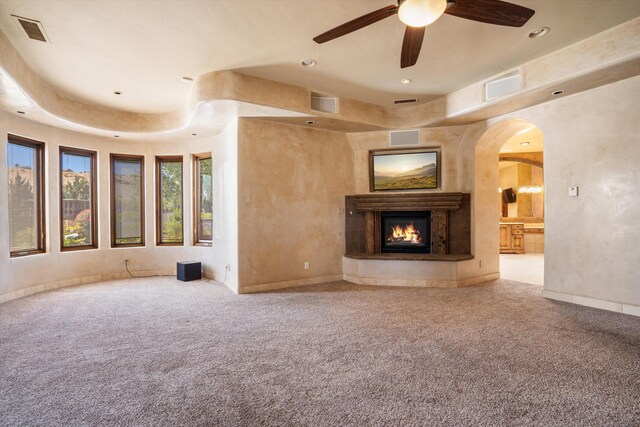 9301 Black Farm Ln NW, Albuquerque, NM 87114 - unfurnished living room featuring a glass covered fireplace, carpet flooring, ceiling fan, arched walkways, and recessed lighting