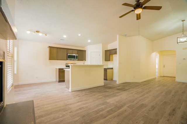 7113 Avignon Ct NW, Albuquerque, NM 87114 - kitchen with stainless steel microwave, a ceiling fan, open floor plan, arched walkways, and a center island with sink