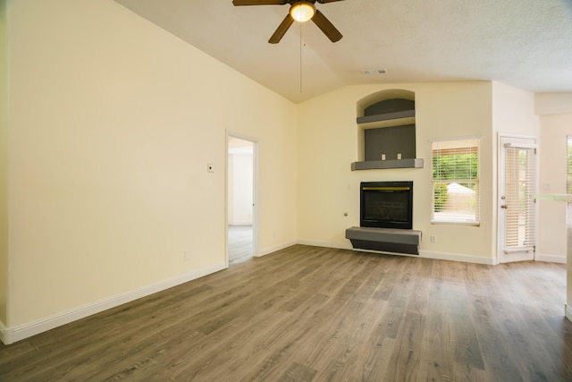 7113 Avignon Ct NW, Albuquerque, NM 87114 - unfurnished living room with a glass covered fireplace, a ceiling fan, wood finished floors, vaulted ceiling, and baseboards